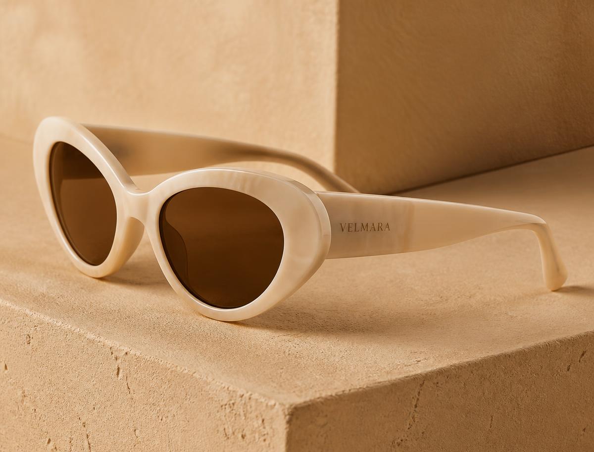 Sculptural bone acetate sunglasses resting on a warm plaster surface